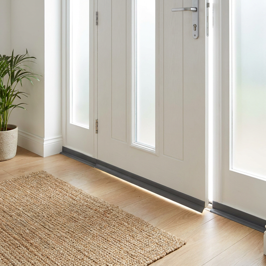 Self-adhesive door seal strip installed on white front door blocking draft