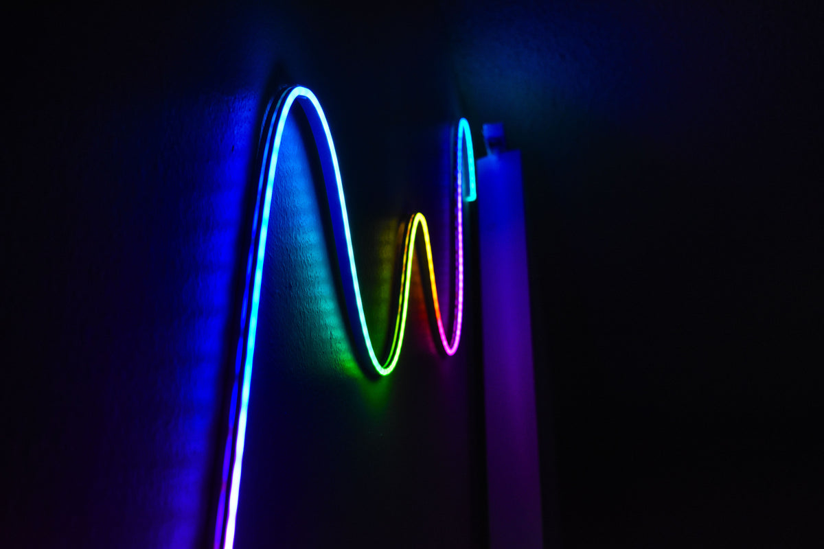RGB LED strip lights with multicolor gradient effect illuminating a bedroom setup